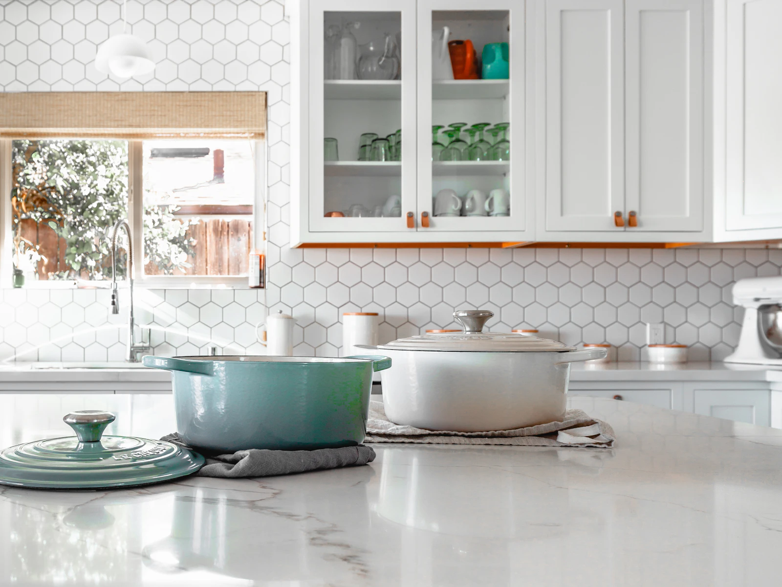 White kitchen with marble surfaces and simple utensils.