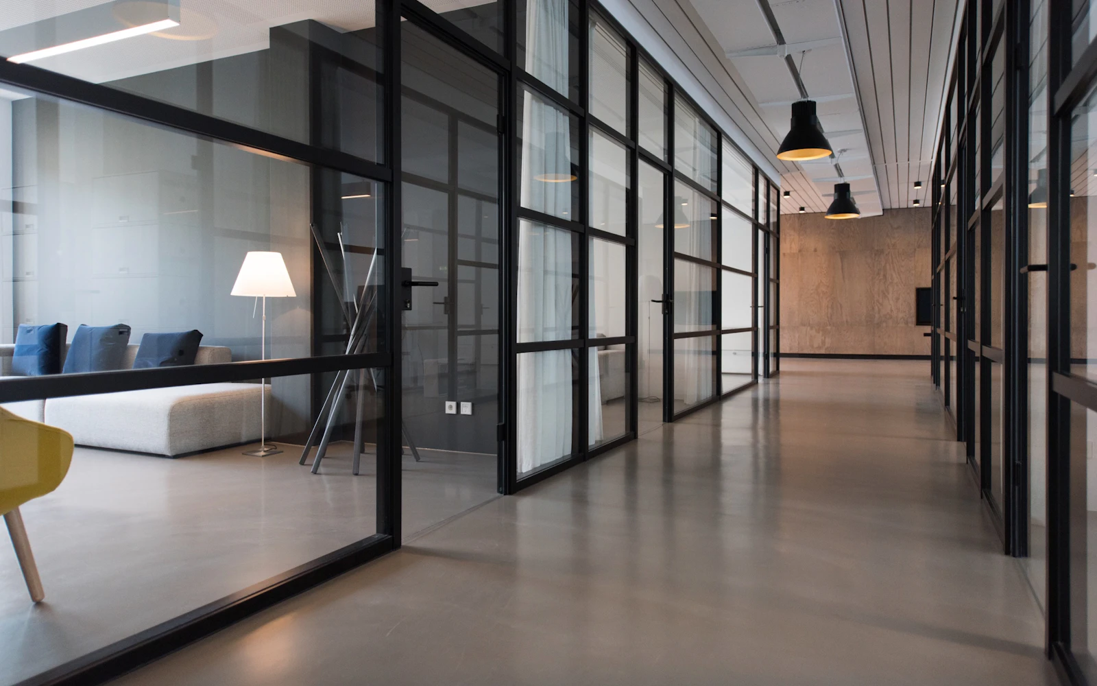 Quiet office lounge with a dark sofa and glass walls.